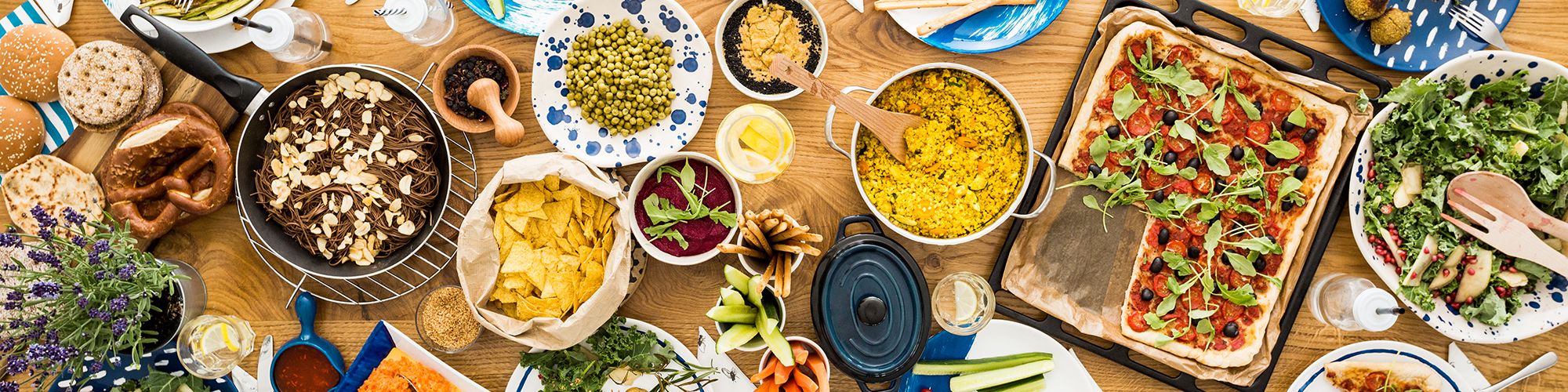 large horizontal wooden table filled with various vegetarian food dishes